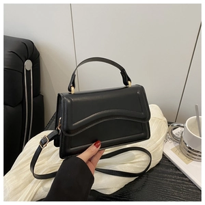 Detail shot of a black leather handbag featuring stylish wavy quilting and gold hardware