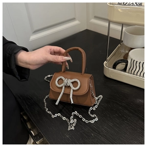 Detail van de bruine lederen mini-tas met strass-strik en zilveren ketting