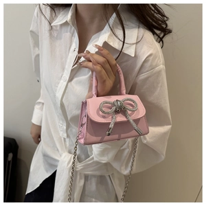 Detail van roze mini-tas met luxe strass-strik en zilverkleurige kettingriem