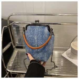 Détail du sac docteur en denim bleu avec fermoir métallique et poignée en cuir marron