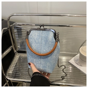 Détail du sac seau en denim bleu clair avec paillettes et fermoir métallique argenté chic