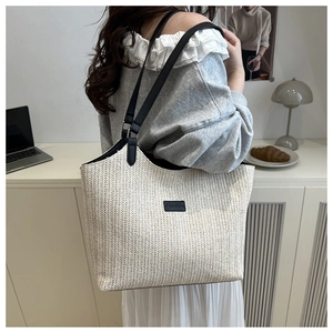 Détail du cabas tissé beige avec texture ondulée et anses en cuir noir sur un bureau