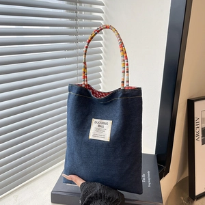 Borsa tote in denim retrò con manici intrecciati colorati ed etichetta bianca vintage
