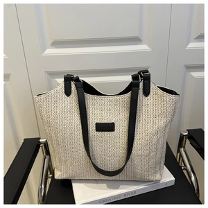 Détail de ce sac fourre-tout en paille beige avec anses en cuir noir et étiquette