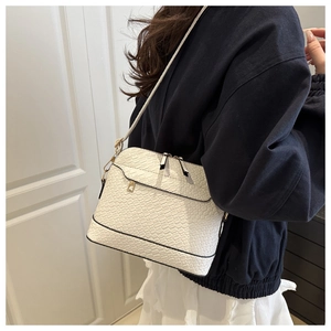 Detail of white crocodile pattern square bag with gold hardware and wide shoulder strap