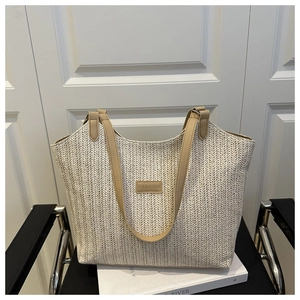 Gros plan sur un sac cabas tressé beige avec sangles en cuir et étiquette FASHION