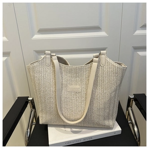 Vue détaillée de la texture de paille tissée et de l'écusson en cuir du sac cabas beige