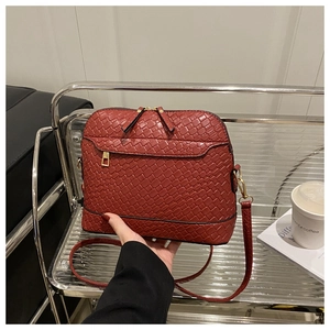 Detail of dark red woven texture leather crossbody bag with gold metal zippers and strap