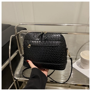 Close-up of black woven leather texture and gold zipper detail on shell-shaped bag