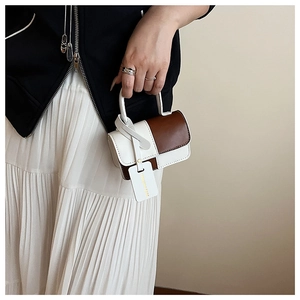 Fashionable contrast stitched mini handbag held by model in casual stylish outfit