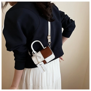 Detailed view of bicolor white and brown crossbody bag styled with a summer outfit
