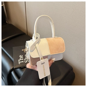 Detailed view of the contrast color stitching and logo tag on a chic small square handbag