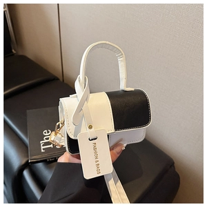 Detail of black and white leather handbag with gold hardware and fashion hangtag