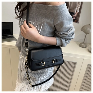 Detail of black PU crossbody bag featuring light gold metal buckles and chain strap
