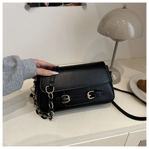 Detail of black crossbody bag with gold hardware and dual straps in a lifestyle setting