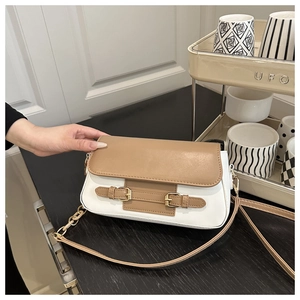 Detail of a minimalist white and brown contrast crossbody bag with gold buckle accents
