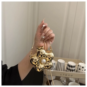 Detailed view of a gold flower mini bag with a large pearl center and snake chain strap