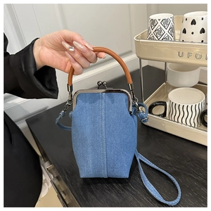 Detail of vintage denim crossbody phone bag with leather handles and metal clasp