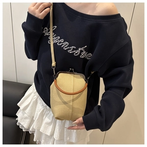 Close-up of a vintage beige canvas kiss-lock crossbody bag with a round brown handle