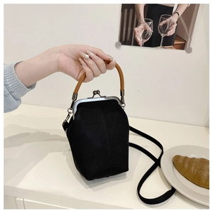 Detail of vintage black canvas mini doctor bag with metal frame clasp and brown leather handle