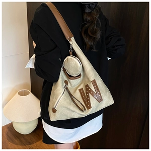 Detalle de bolso tote de lona con letra W de cuero, remaches y monedero redondo incluido