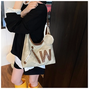 Detalle de bolso de lona con letra W de cuero y accesorio de monedero redondo