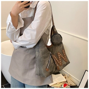 Detail view of large grey tote bag with rivet letter W and side zipper pocket