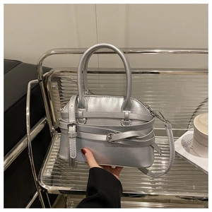 Détail d'un sac coquillage argenté avec sangles croisées et boucles sur une chaise
