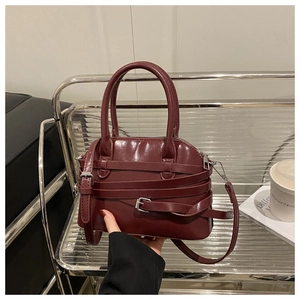 Détail du sac coquillage rouge vin avec finition brillante et boucle sur support métal