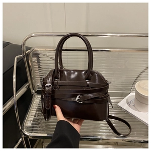 Détail d'un sac à main en cuir marron foncé avec lanières décoratives et boucles métalliques