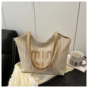 Detail shot of a woven straw tote bag with brown PU handles on an artistic setup