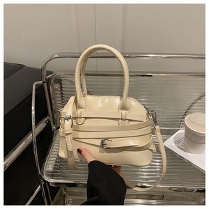 Détail du sac à main crème montrant les lanières décoratives et la boucle métallique