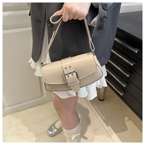 Detail of beige glossy leather handbag with silver buckle and adjustable shoulder strap