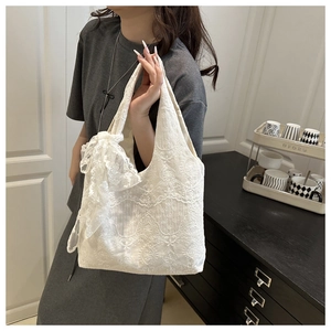 Close-up of white lace tote bag featuring intricate floral crochet and a large bow detail