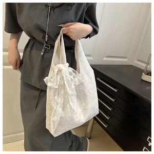 Detailed view of white floral lace tote bag with delicate embroidery and decorative bow