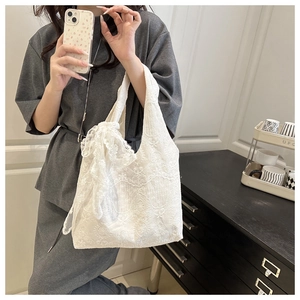 Close-up of white lace tote bag featuring elegant floral embroidery and ribbon detail