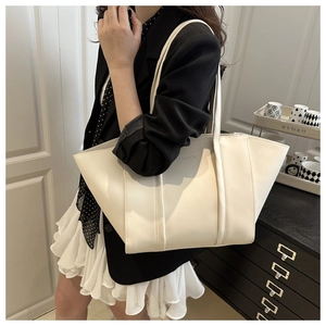 Detail shot of a cream white PU leather tote bag with embossed FASHION lettering