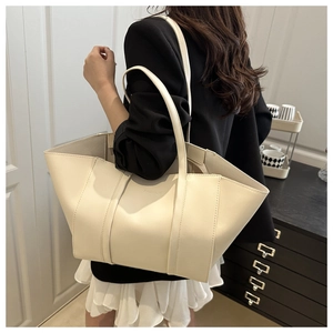 Model wearing a large cream tote bag with fashion embossing and vertical seam stripes