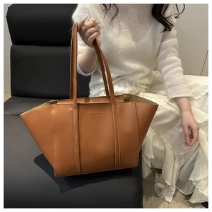 Detail of caramel brown faux leather tote with embossed FASHION logo and long handles