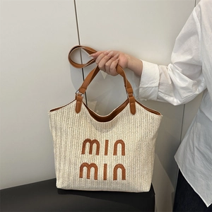 Straw woven tote bag with brown leather straps and lettering for beach vacations