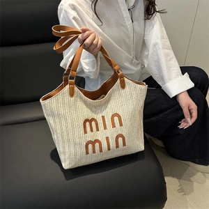Woven straw tote bag with brown leather handles and min min logo for summer beach vacations