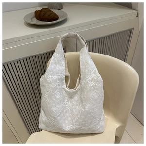 Detailed close-up of intricate lace floral embroidery on the cream white tote bag