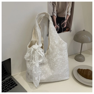 Detailed view of white floral lace tote bag with a large decorative bow on the side