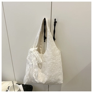Close-up of white lace tote bag featuring floral embroidery and decorative ribbon bow