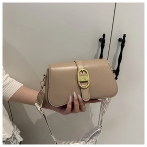 Detail of a chic crossbody bag with a large gold buckle and patterned wide shoulder strap