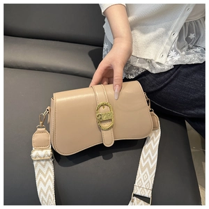 Close-up of beige leather crossbody bag with golden horseshoe buckle and wavy strap