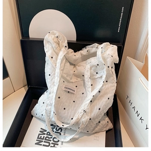Detailed view of floral tote bag in gift box with white bubble pleated fabric and black print