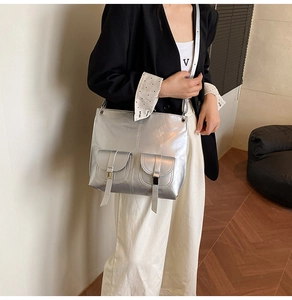 Silver metallic square tote bag with pocket details and ring handles on a model
