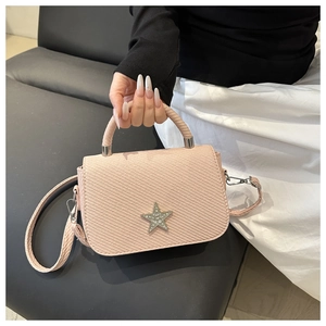 Detail einer rosa geflochtenen Handtasche mit glitzerndem Sternemblem und Tragegriff