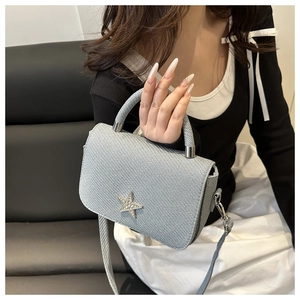 Detailansicht der gewebten silbernen Handtasche mit diamantbesetztem Stern und Metallbeschlägen